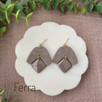 Top view of a pair of dark brown colored earrings with a scalloped texture displayed on a white scalloped tray.