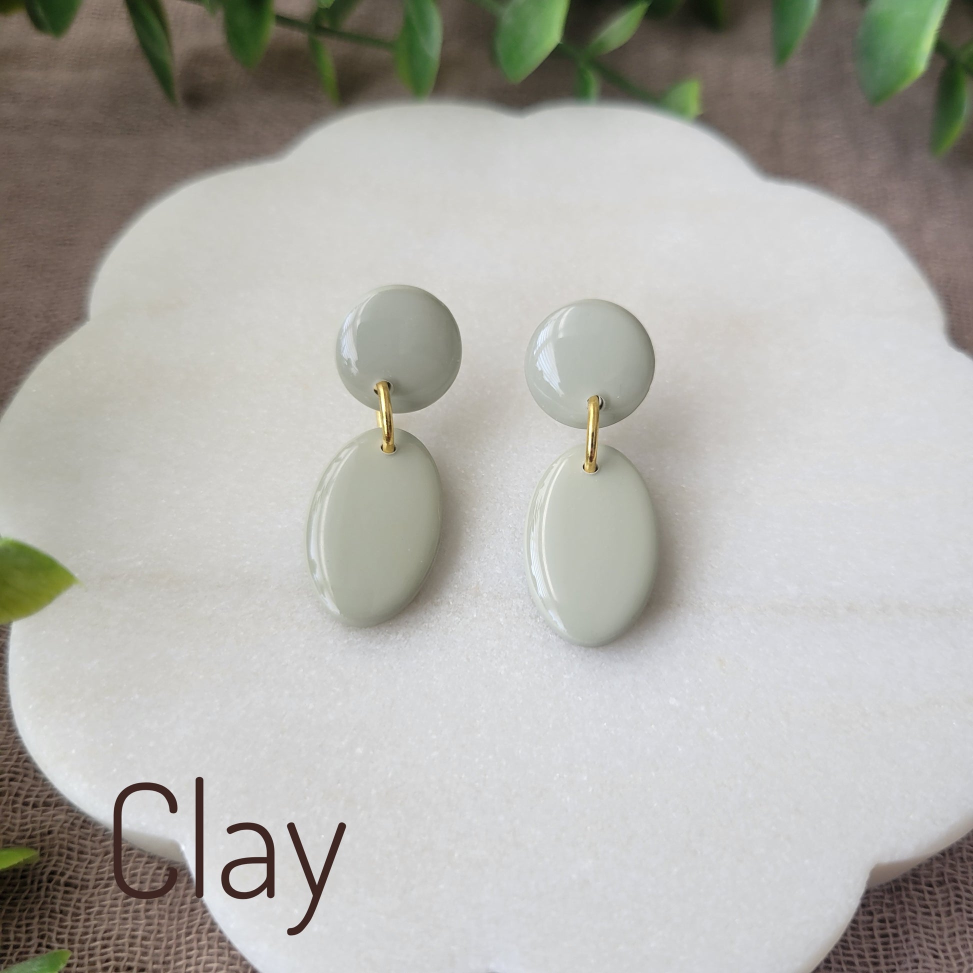 Top view of green colored earrings displayed on a white round scalloped tray.