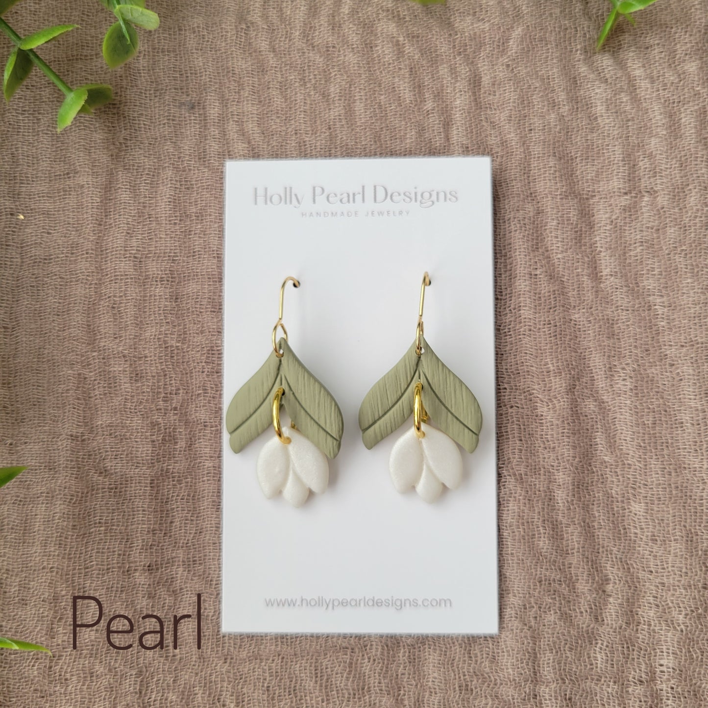 Top view of a pair of pearl tulip shaped earrings displayed on a white earring card.
