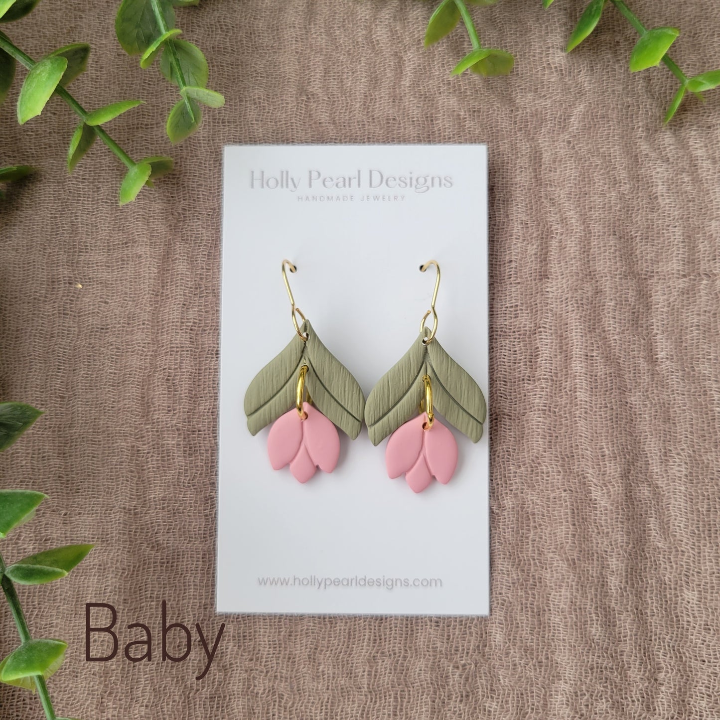 Top view of a pair of pink tulip shaped earrings displayed on a white earring card.