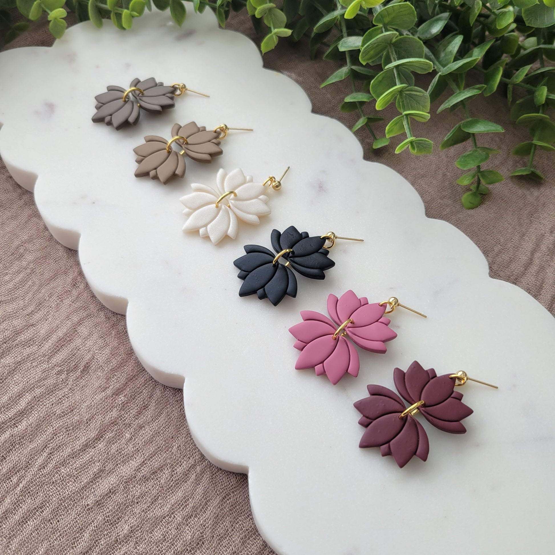 Right view of six lotus shaped earrings displayed on a white scalloped tray.