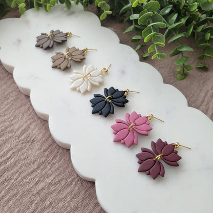 Right view of six lotus shaped earrings displayed on a white scalloped tray.