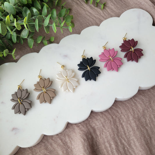 Left view of six lotus shaped earrings displayed on a white scalloped tray.