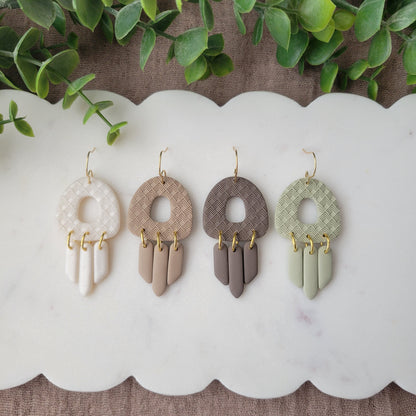 Top view of four earrings with lattice texture displayed on a white scalloped tray.