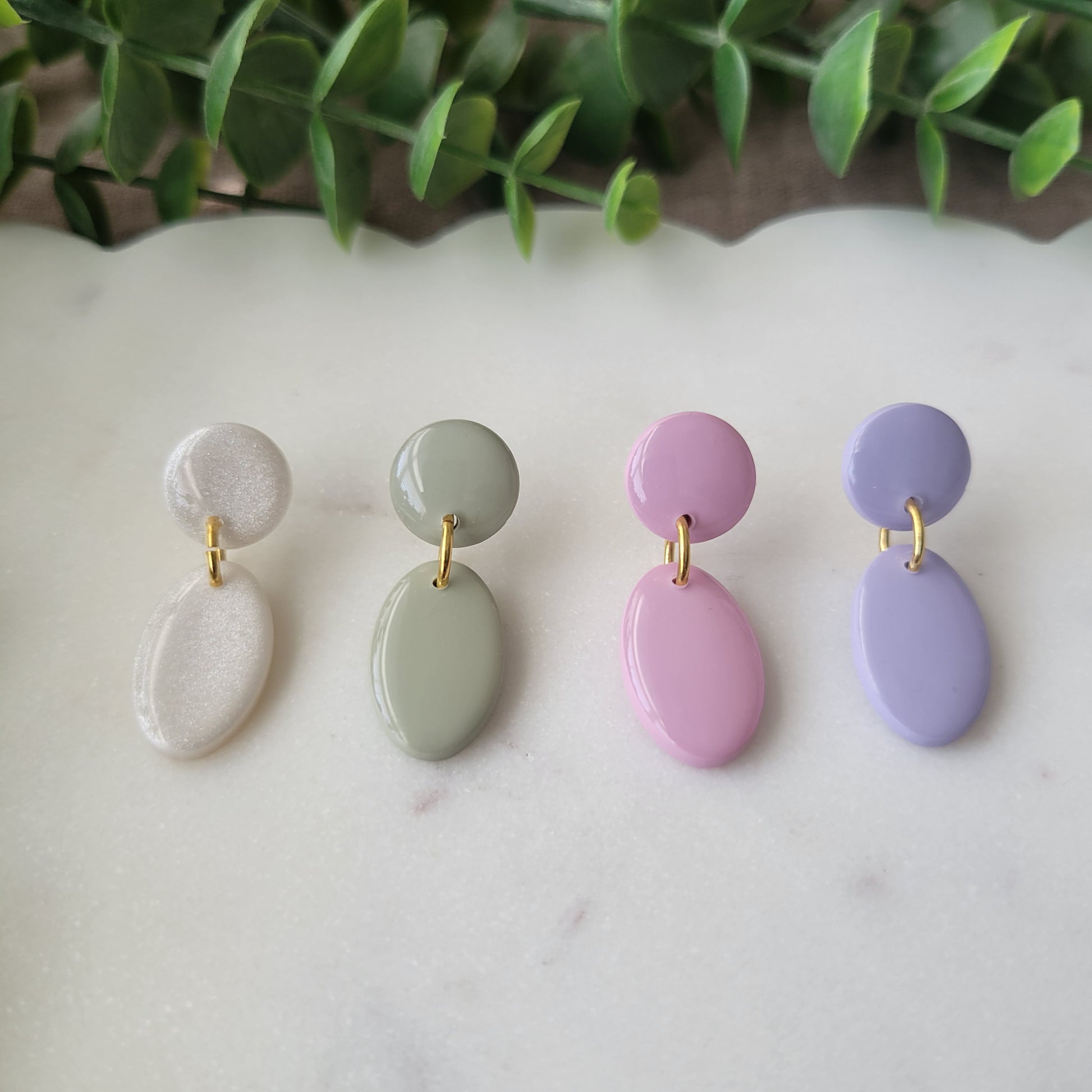 Front view of four earrings displayed on a white scalloped tray.