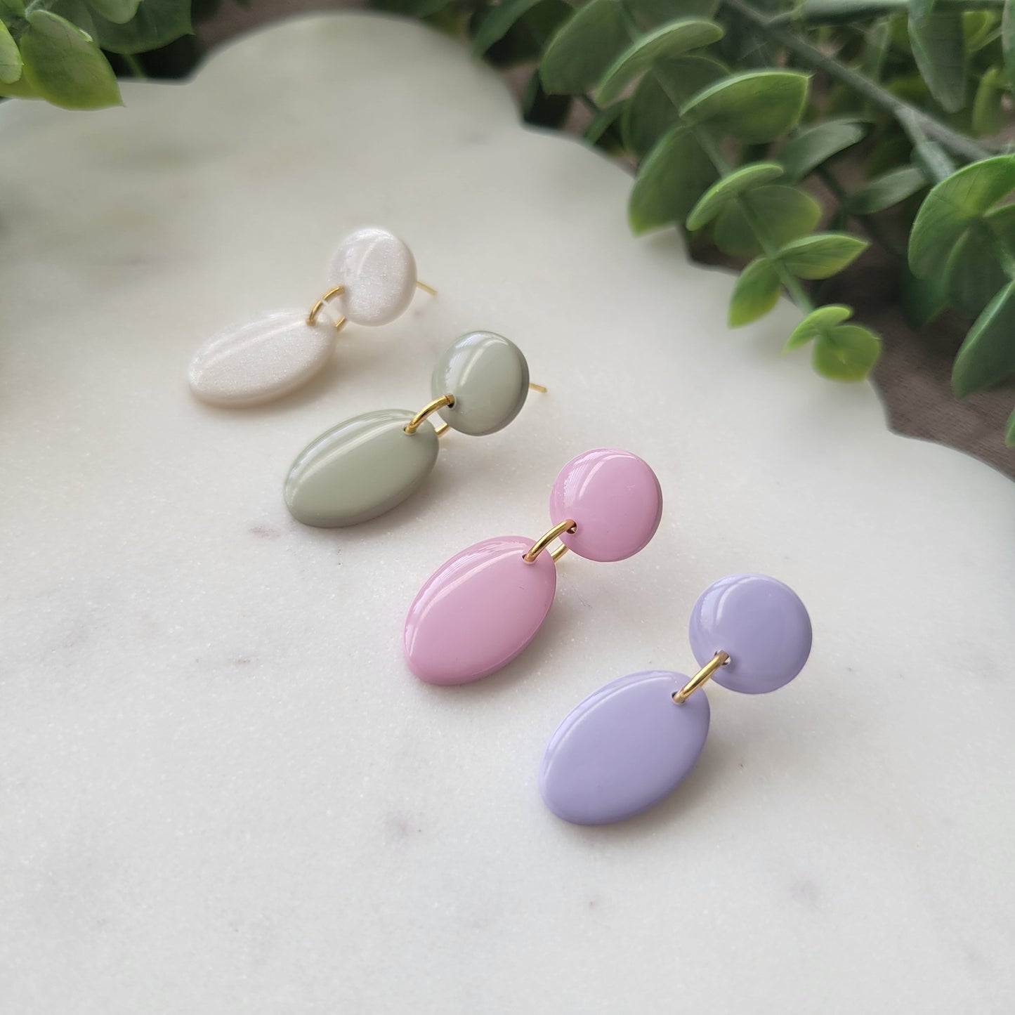 Right side view of four earrings displayed on a white scalloped tray.