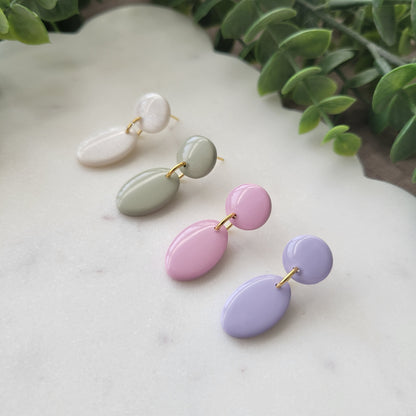 Right side view of four earrings displayed on a white scalloped tray.