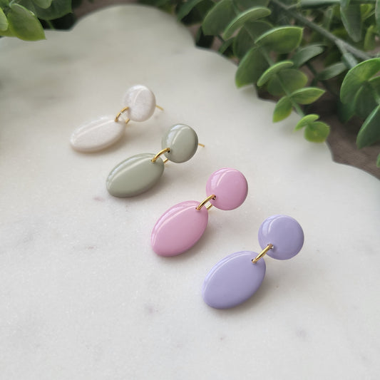 Right side view of four earrings displayed on a white scalloped tray.