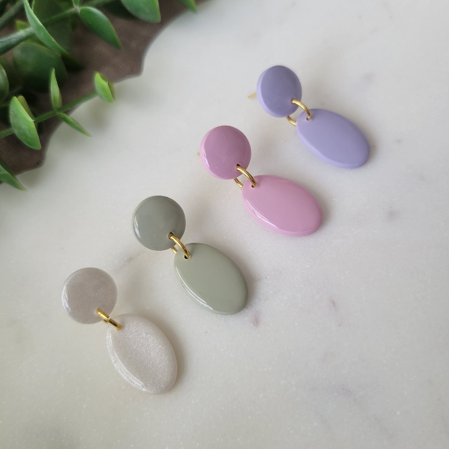 Left side view of four earrings displayed on a white scalloped tray.