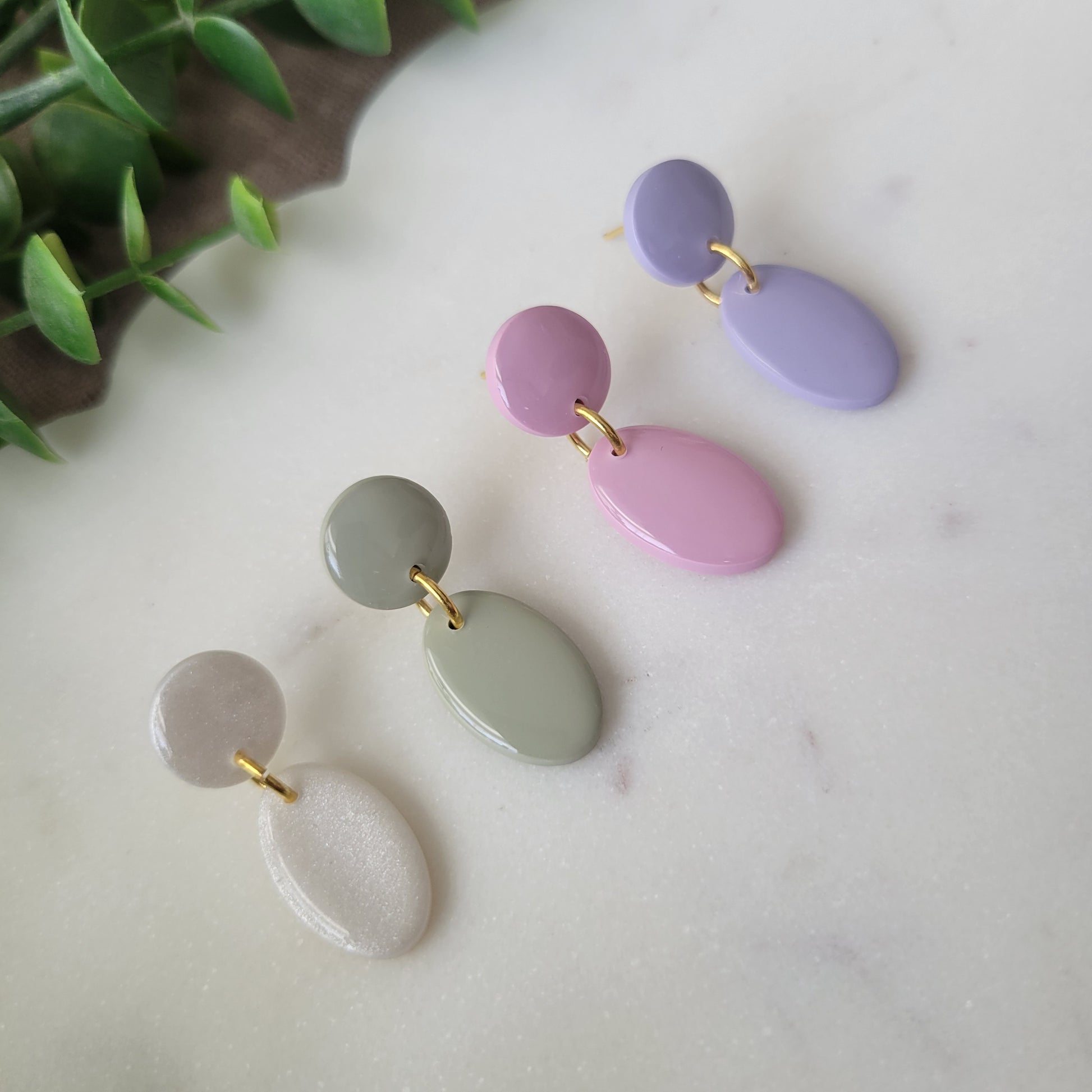 Left side view of four earrings displayed on a white scalloped tray.