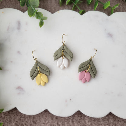 Top view of three tulip shaped earrings displayed on a white scalloped tray.